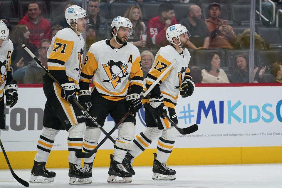Pittsburgh Penguins right wing Bryan Rust (17) celebrates his goal with Kris Letang (58) and Evgeni Malkin (71) during the first period of a preseason NHL hockey game against the Detroit Red Wings Monday, Oct. 3, 2022, in Detroit. (AP Photo/Paul Sancya)