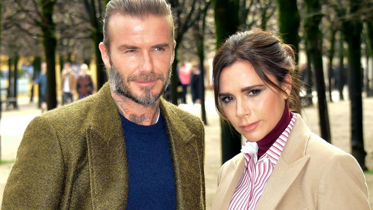 Victoria Beckham standing outside with her husband David