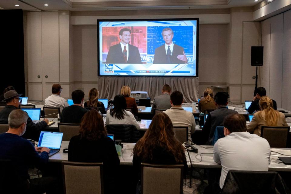PHOTO: Florida Governor and Republican presidential hopeful Ron DeSantis and California Governor Gavin Newsom appear on a screen in the press room during a debate in Alpharetta, Georgia, Nov. 30, 2023.  (Christian Monterrosa/AFP via Getty Images)