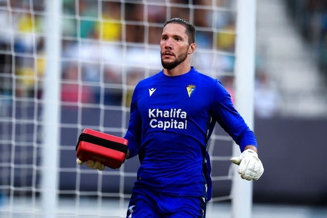 Cadiz’s goalkeeper Jeremias Ledesma brings a defibrillator as a supporter is attended by a medical team in the stands