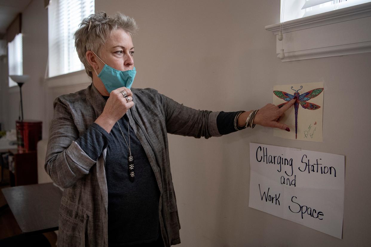 Amanda Pace Kollar, Operation Director of the Code Purple shelter at Trinity United Methodist Church in West Asheville, points out tear stains left by the artist of an image hanging in the community hall January 13, 2022. "She was thinking about her children while working on it," said Kollar, who encourages winter guests to showcase their work on the walls and express their inner child.