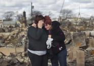 Las vecinas Lucille Dwyer (D) y Linda Strong se consuelan mutuamente tras mirar los destrozos en su barrio, el cual se incendió por cuenta de Sandy, en la zona de Breezy Point, distrito de Queens, nueva York, el 31 de octubre de 2012. REUTERS/Shannon Stapleton