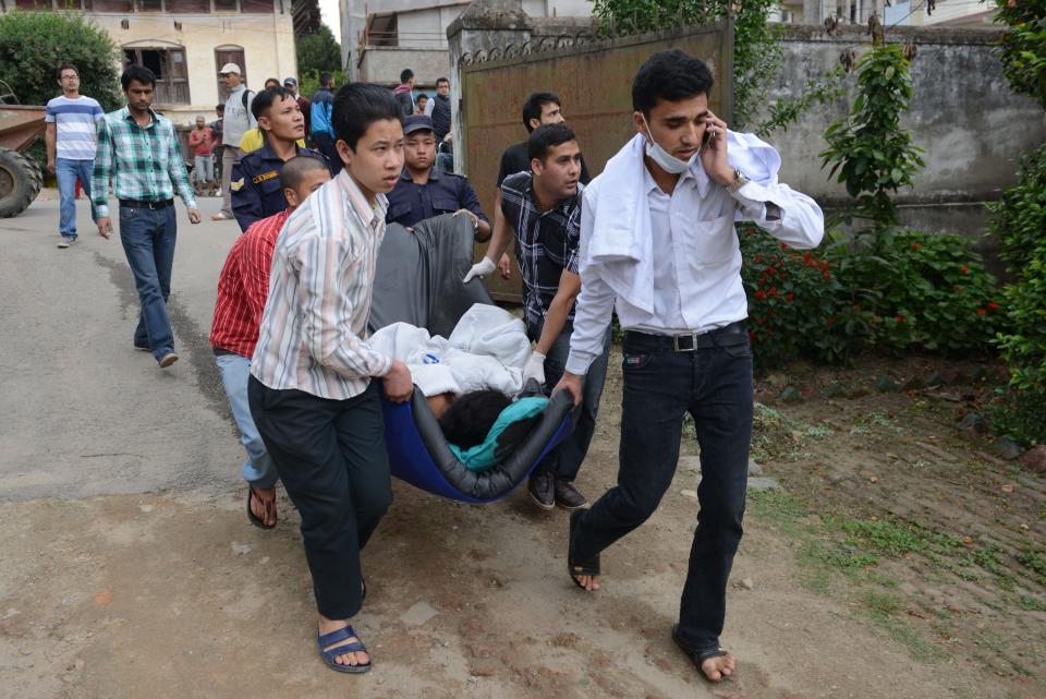 Nepalese health workers carry injured people into an open area following an earthquake, at Lalitpur on the outskirts of Kathmandu on April 25, 2015.  (PRAKASH MATHEMA/AFP/Getty Images)