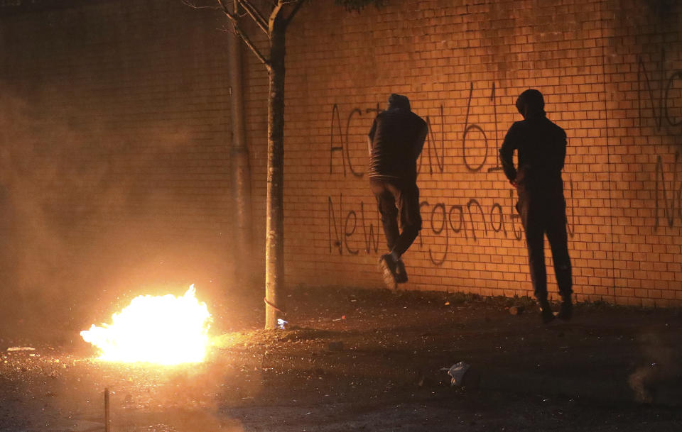 Nationalists jump to avoid a petrol bomb thrown by Loyalists over the peace wall in West Belfast, Northern Ireland, Wednesday, April 7, 2021. The police had to close roads into the near by Protestant area as Nationalist and Loyalist attacked each other. (AP Photo/Peter Morrison)