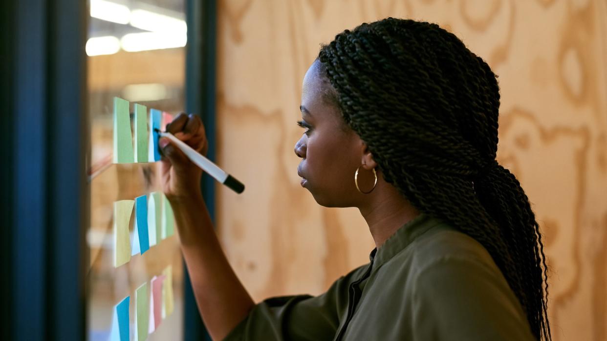 Cropped shot of a young designer writing her ideas on adhesive notes.