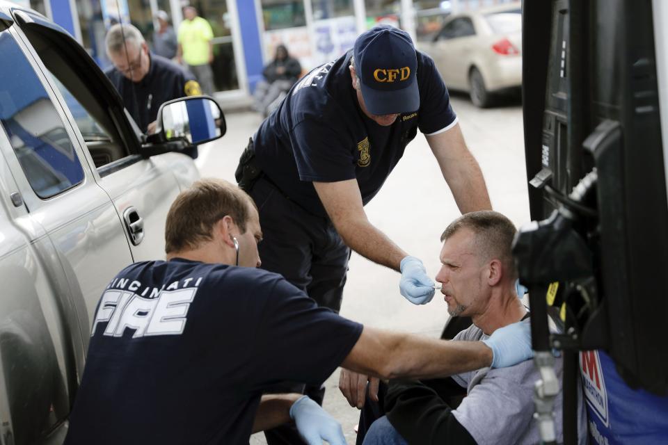 FILE - In this Nov. 2, 2017, file photo, medics with the Cincinnati Fire Department work to keep a possible overdose victim awake after administering Naloxone while responding to a call at a gas station in downtown Cincinnati. Reports emerging about a possible financial settlement in 2019 with Purdue Pharma, the company that has come to symbolize the nation's opioid epidemic, suggests the settlement amount won't come anywhere near what the national crisis has cost. (AP Photo/John Minchillo, File)