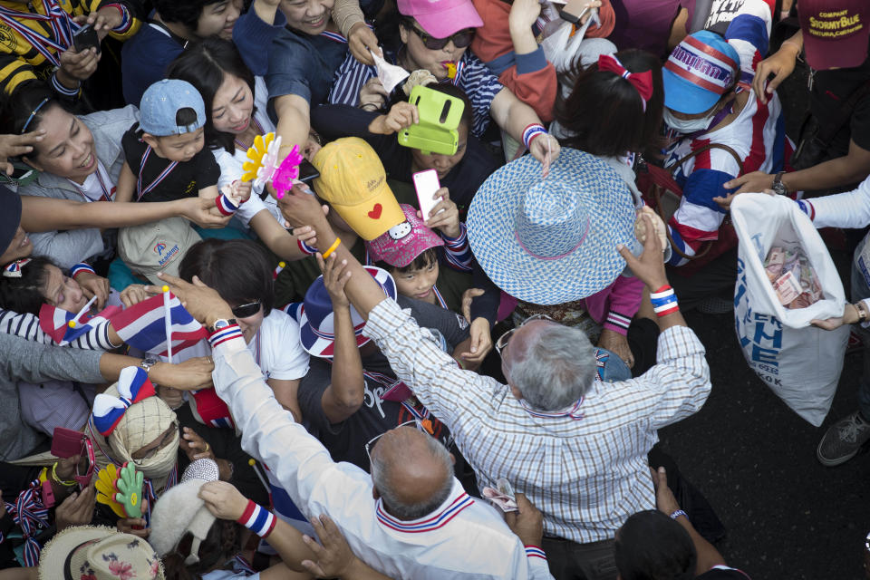 A girl looks up at anti-government protest leader Suthep Thaugsuban, bottom right, as he greets supporters and collects donations, Sunday, Jan. 19, 2014, in Bangkok. Two explosions shook an anti-government demonstration site in Thailand's capital on Sunday, wounding at least 28 people in the latest violence to hit Bangkok as the nation's increasingly volatile political crisis drags on. (AP Photo/John Minchillo)