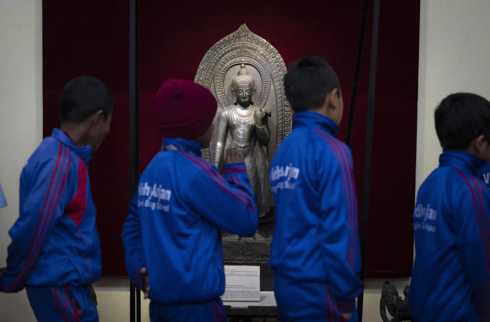 Un grupo de alumnos de una escuela observan una estatua de Buddha que había sido robada en penal y fue devuelta por el Museo Metropolitano de Arte de Nueva York, en una exposición en el Museo Nacional de Katmandú, Nepal, el 3 de enero de 2024. En el pasado, un número desconocido de estatuas sagradas de deidades hindúes fueron robadas y llevadas ilegalmente al extranjero. Ahora, docenas de ellas están siendo repatriadas a la nación del Himalaya como parte de un creciente esfuerzo global para regresarlas. (AP Foto/Niranjan Shrestha)