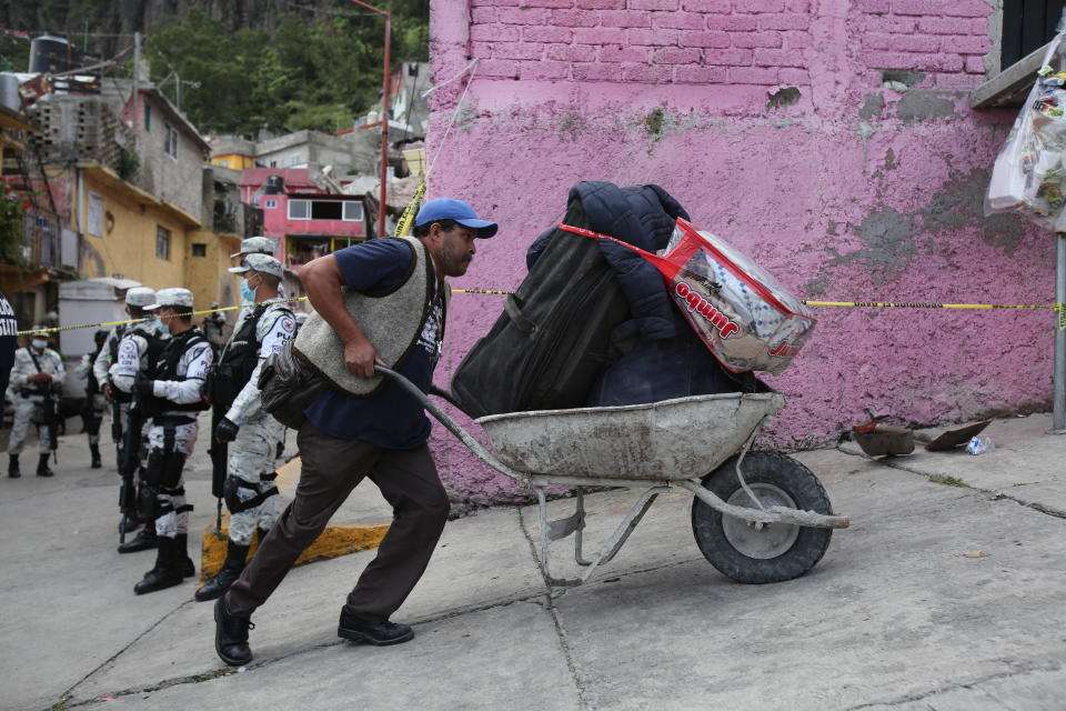 An evacuee uses a wheelbarrow to transport his belongings away from the site of a landslide that brought tons of massive boulders down on a steep hillside neighborhood, in Tlalnepantla, on the outskirts of Mexico City, Saturday, Sept. 11, 2021. A section of the peak known as Chiquihuite gave way Friday afternoon, plunging rocks the size of small homes onto the densely populated neighborhood. (AP Photo/Ginnette Riquelme)