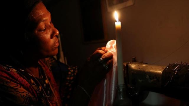 Dressmaker Faieza Caswell from Mitchells Plain sews under candlelight in her workplace, on the Cape Flats due to South Africa&#39;s struggling power utility company Eskom, implementing regular power cuts - called &#39;load-shedding&#39;, in Cape Town, South Africa February 11, 2023
