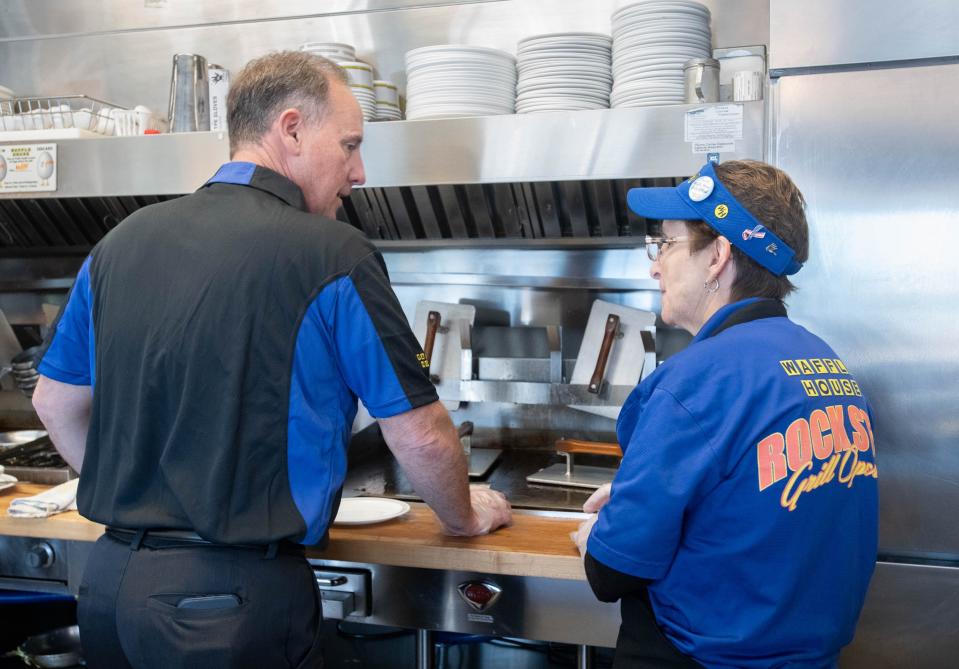 Chris Baker, right, gives a few pointers to Mark Faulkner, Baptist Health Care CEO, as he works the grill at the Waffle House on Brent Lane in Pensacola on Wednesday, Oct. 18, 2023.
