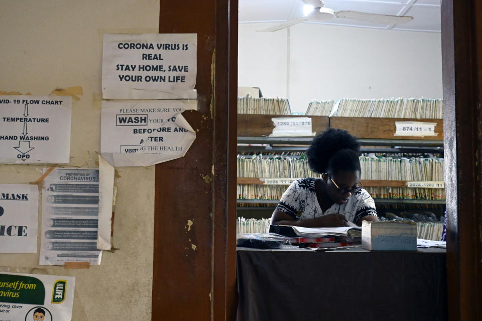 Un agent de santé est assis derrière une table dans le hall d'une clinique à Adukrom, au Ghana, le 27 avril 2022. Photo prise le 27 avril 2022. REUTERS/Cooper Inveen