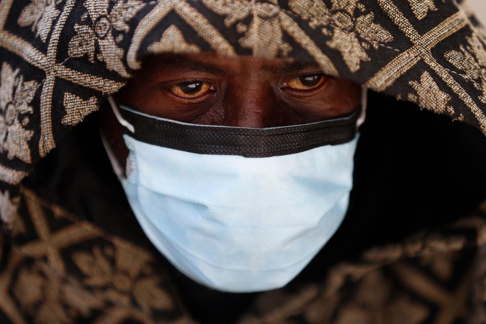A man wears a protective mask while waiting for a bus in Detroit, Wednesday, April 8, 2020. Detroit buses will have surgical masks available to riders starting Wednesday, a new precaution the city is taking from the new coronavirus COVID-19.