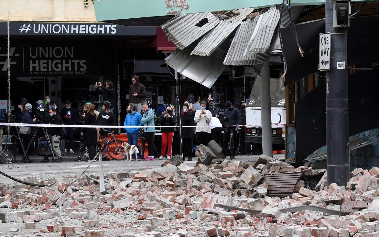 Residents gather near a damaged building in the popular shopping Chappel Street in Melbourne on Wednesday - William West /AP