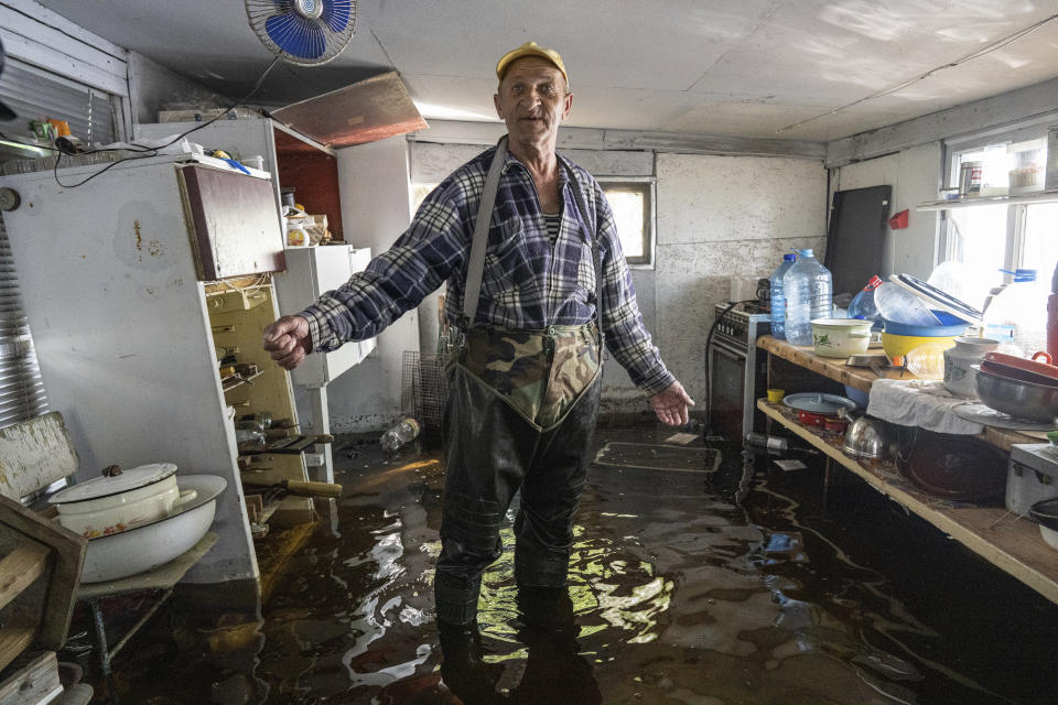 Mykola Gurzhiy, 74, a local fisherman stands at the kitchen of his flooded house in the island of Kakhovka reservoir on Dnipro river near Lysohirka, Ukraine, Thursday, May 18, 2023. Damage that has gone unrepaired for months at a Russian-occupied dam is causing dangerously high water levels along a reservoir in southern Ukraine. (AP Photo/Evgeniy Maloletka)