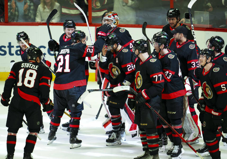 Ottawa Senators right wing Claude Giroux (28) is swarmed by teammates as they help him celebrates his 1000th career point after assisting a goal against the Carolina Hurricanes in the first period of an NHL hockey game in Ottawa, Ontario, Monday, April 10, 2023. (Sean Kilpatrick/The Canadian Press via AP)