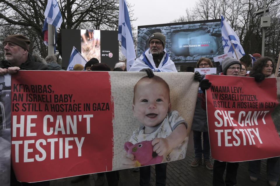 Protesters waving flags and pictures of the hostages kidnapped during the Oct. 7 Hamas cross-border attack in Israel, attend a protest outside the International Court of Justice in The Hague, Netherlands, Friday, Jan. 12, 2024. The United Nations' top court opened hearings Thursday into South Africa's allegation that Israel's war with Hamas amounts to genocide against Palestinians, a claim that Israel strongly denies. (AP Photo/Patrick Post)