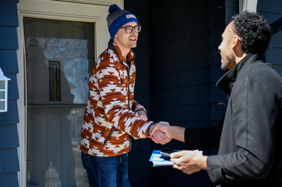 Chris Huffman, left, shakes hands with Jon Horford, a democratic candidate for Michigan's new 77th State House district, while Horford campaigns door to door on Tuesday, March 29, 2022, in Lansing.