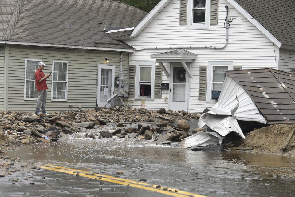 A man surveys damage to a house on Hamilton Street in Leominster, Mass. after heavy rain fall in the town overnight. (AP Photo/Josh Reynolds)