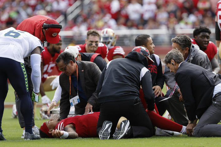 San Francisco 49ers head coach Kyle Shanahan, top left, checks on quarterback Trey Lance, bottom, who lies on the field after being tackled during the first half of an NFL football game against the Seattle Seahawks in Santa Clara, Calif., Sunday, Sept. 18, 2022. (AP Photo/Josie Lepe)