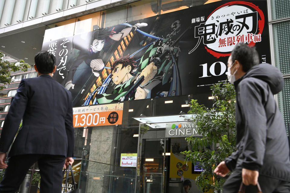 People walk past a theater where the film “Demon Slayer: Kimetsu no Yaiba the Movie: Mugen Train" is screened on its opening day, Oct. 16, 2020. “Demon Slayer,” directed by Haruo Sotozaki, has become the biggest grossing film for Japan, including live-action films, and has struck a chord with pandemic-era Japan, and possibly with the world. (Tsuyoshi Ueda/Kyodo News via AP)