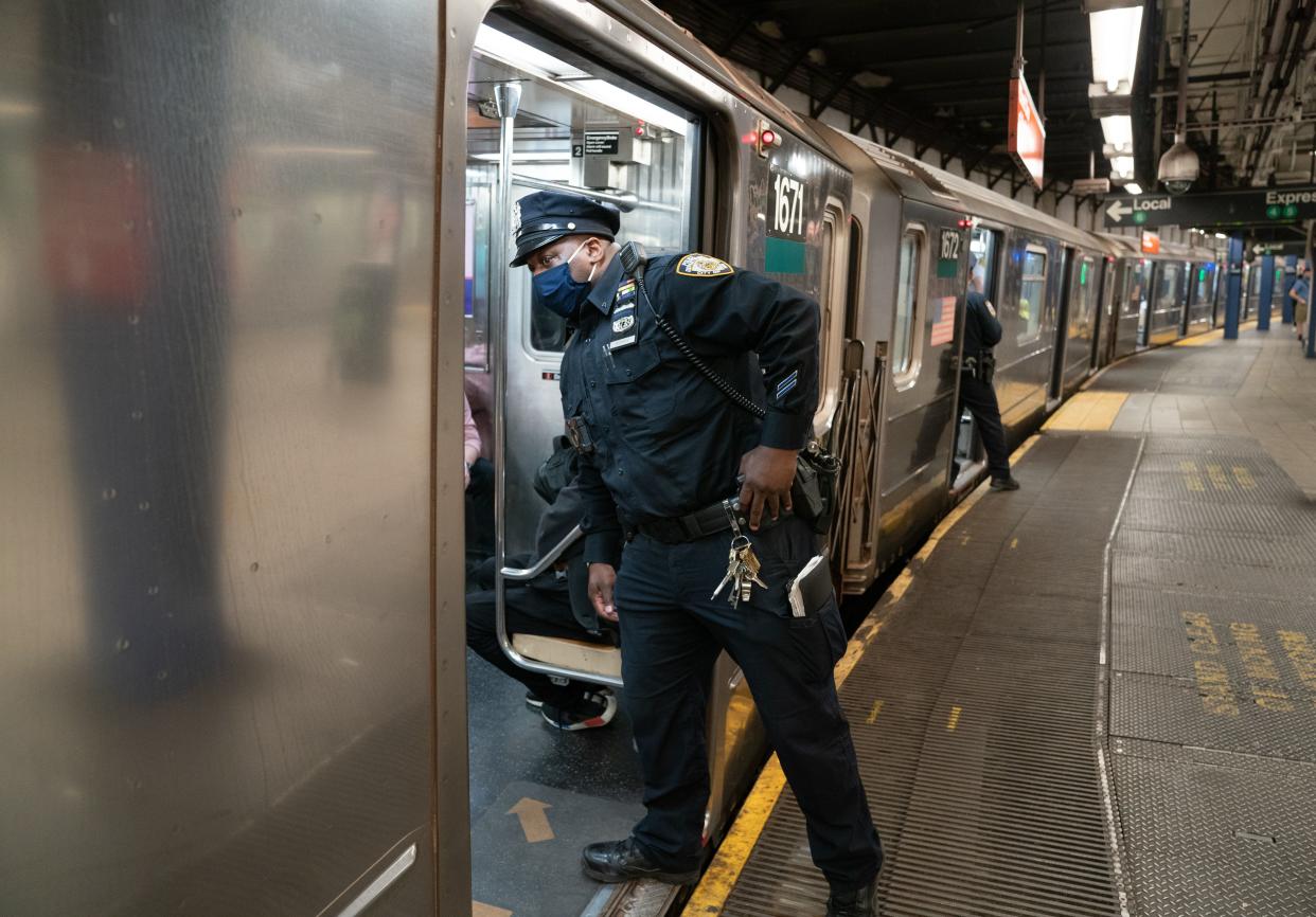 A NYPD officer checks a 6 subway train as it pulls into Union Square subway station in Manhattan, New York.