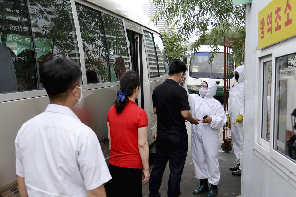 FILE - In this undated file photo provided on Sept. 10, 2020, by the North Korean government, a health worker checks the temperature of people to protect against the coronavirus in Pyongyang, North Korea. The coronavirus is the biggest reason for North Korea’s absence from the Tokyo Games. Always highly sensitive to communicable disease outbreaks, the nation has shut its borders tighter than normal, worried that its fragile health care system and rickety economy could not withstand a major outbreak. (Korean Central News Agency/Korea News Service via AP, File)