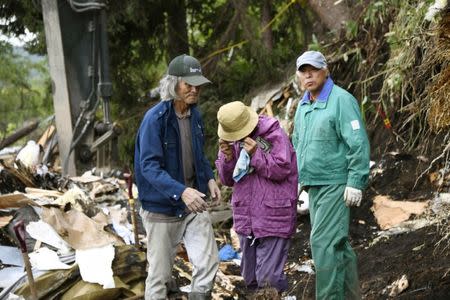 A woman (C) wipes her tears after her missing father was found at an area damaged by a landslide caused by an earthquake in Atsuma town, Hokkaido, northern Japan, in this photo taken by Kyodo September 7, 2018. Mandatory credit Kyodo/via REUTERS