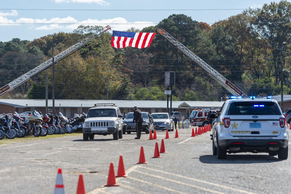 Mourners arrive under a U.S. flag mounted by the local fire departments during the memorial service for slain Lowndes County Sheriff "Big John" Williams, Monday, Dec. 2, 2019, in Montgomery, Ala. (AP Photo/Vasha Hunt)