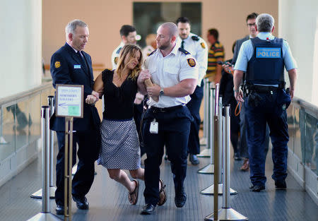 Security guards hold a protester as they remove a group from the House of Representatives after they began chanting slogans regarding the offshore detention of asylum seekers during Question Time in Parliament House, Canberra, Australia, November 30, 2016. AAP/Lukas Coch/via REUTERS