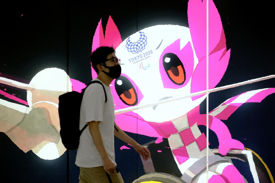 TOKYO, JAPAN - 2021/06/26: A pedestrian wearing a face mask as a precaution walks by signage advertising the Tokyo 2020 Olympic Games. (Photo by James Matsumoto/SOPA Images/LightRocket via Getty Images)