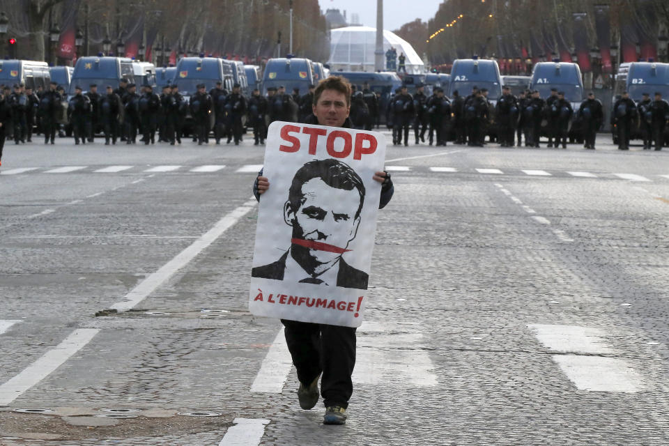 A demonstrator holds a portrait of France’s President Emmanuel Macron during a protest on the Champs-Elysées on Dec. 8. (Photo: Michel Euler/AP)