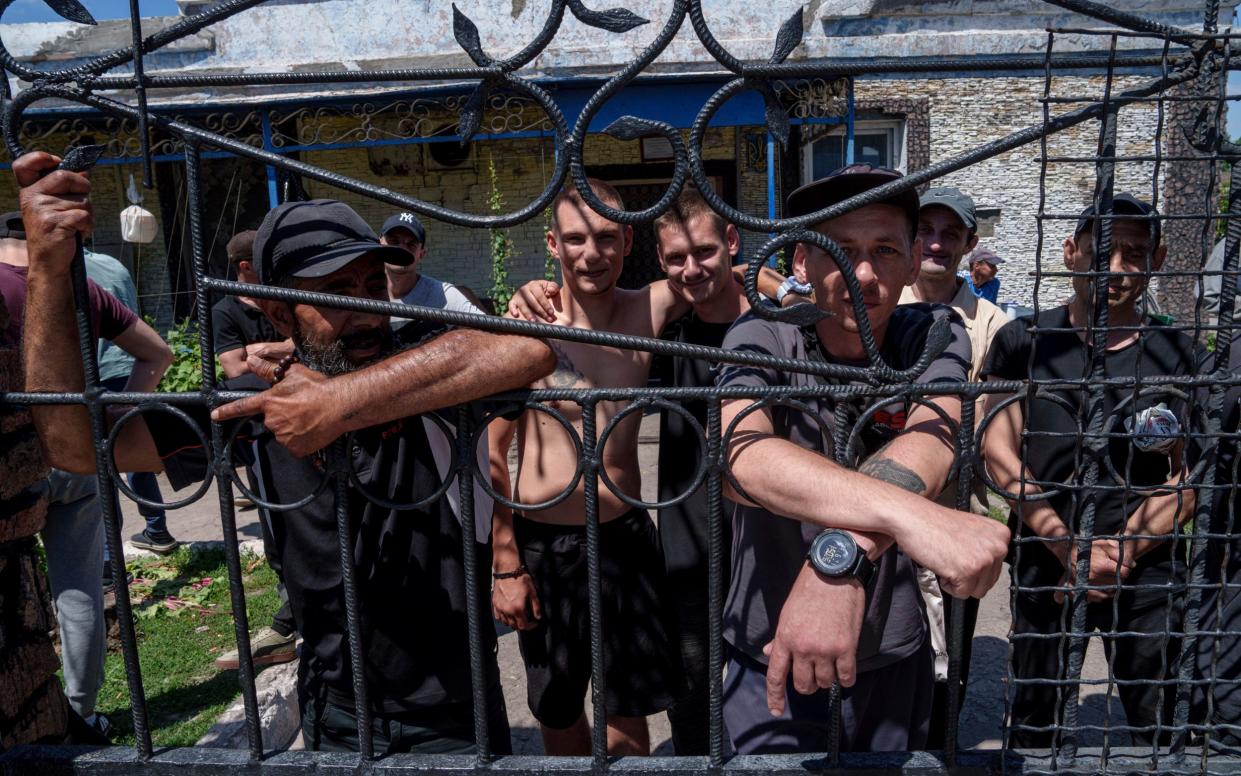 Prisoners stand behind the fence in the barrack's yard in a prison in the Dnipropetrovsk region, Ukraine