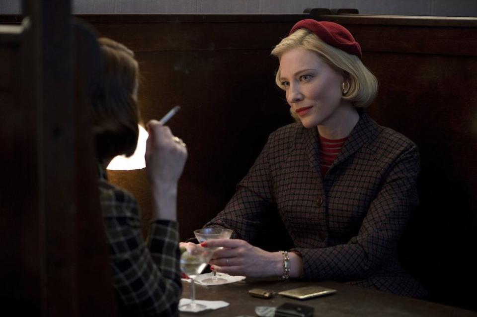 Two women have martinis and smoke in a bar booth