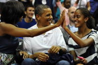 President Barack Obama shares a laugh with his wife Michelle and daughter Malia, as the US Senior Men's National Team and Brazil play during a pre-Olympic exhibition basketball game at the Verizon Center on July 16, 2012 in Washington, DC. (Photo by Patrick Smith/Getty Images)