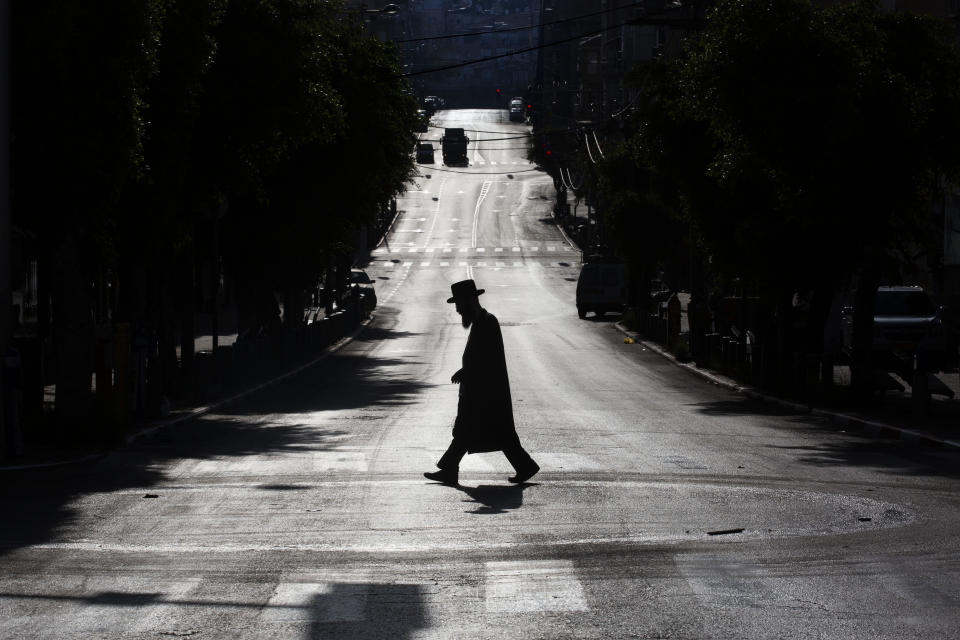 An ultra-Orthodox Jew crosses a mainly deserted street because of the government's measures to help stop the spread of the coronavirus, in Bnei Brak, Israel, Wednesday, April 8, 2020. Israeli Prime Minister Benjamin Netanyahu announced Monday a complete lockdown over the upcoming Passover feast to control the country's coronavirus outbreak, but offered citizens some hope by saying he expects to lift widespread restrictions after the week-long Jewish holiday. (AP Photo/Oded Balilty)
