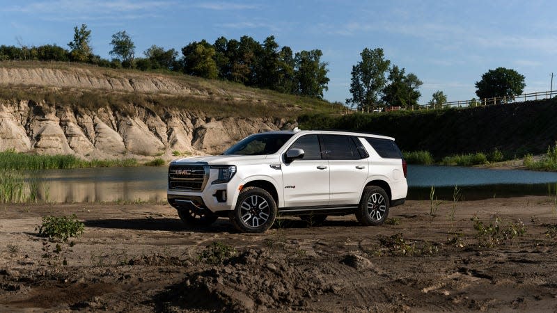 A photo of a white GMC Yukon SUV parked near a lake. 