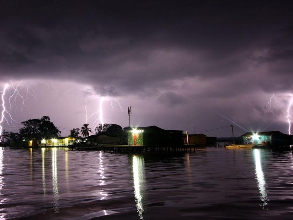 A picture of a lake-side town at night showered by several lightning bolts at once in Maracaibo.