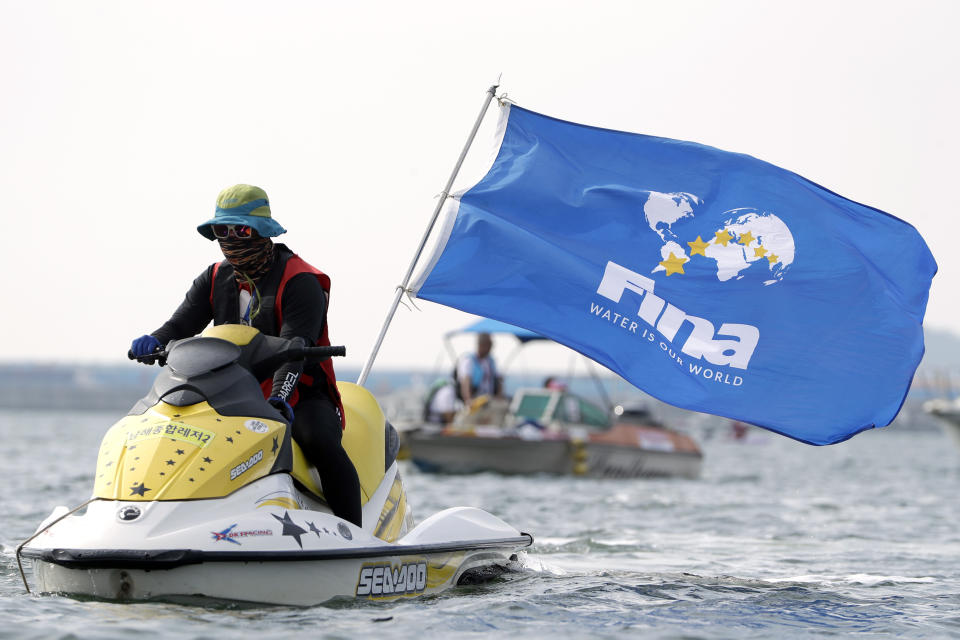 A race official drives a watercraft carrying a FINA flag during the women's 5km open water swim at the World Swimming Championships in Yeosu, South Korea, Wednesday, July 17, 2019. (AP Photo/Mark Schiefelbein)