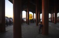 A boy plays in a Chinese traditional pavilion next to an inflated Rubber Duck by Dutch conceptual artist Florentijn Hofman at the Summer Palace in Beijing September 26, 2013. The 18-metre-high (59 ft.) inflatable sculpture will be displayed at the historic tourist attraction for a month, local media reported. REUTERS/Jason Lee (CHINA - Tags: SOCIETY)