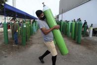 A man carries his empty oxygen tank to be filled after arriving at the head of the line, in the Villa El Salvador neighborhood of Lima, early Thursday morning, Feb. 18, 2021. A crisis over the supply of medical oxygen for coronavirus patients has struck in Africa and Latin America, where warnings went unheeded at the start of the pandemic and doctors say the shortage has led to unnecessary deaths. (AP Photo/Martin Mejia)