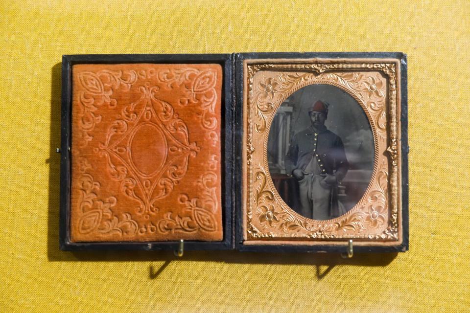 An open, velvet-lined photo folder displaying a tintype.