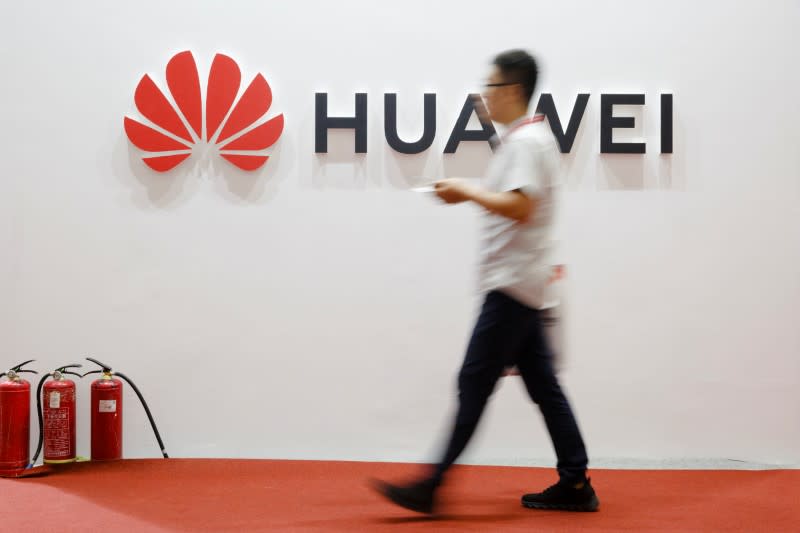 A man walks past a Huawei company logo at the International Consumer Electronics Expo in Beijing