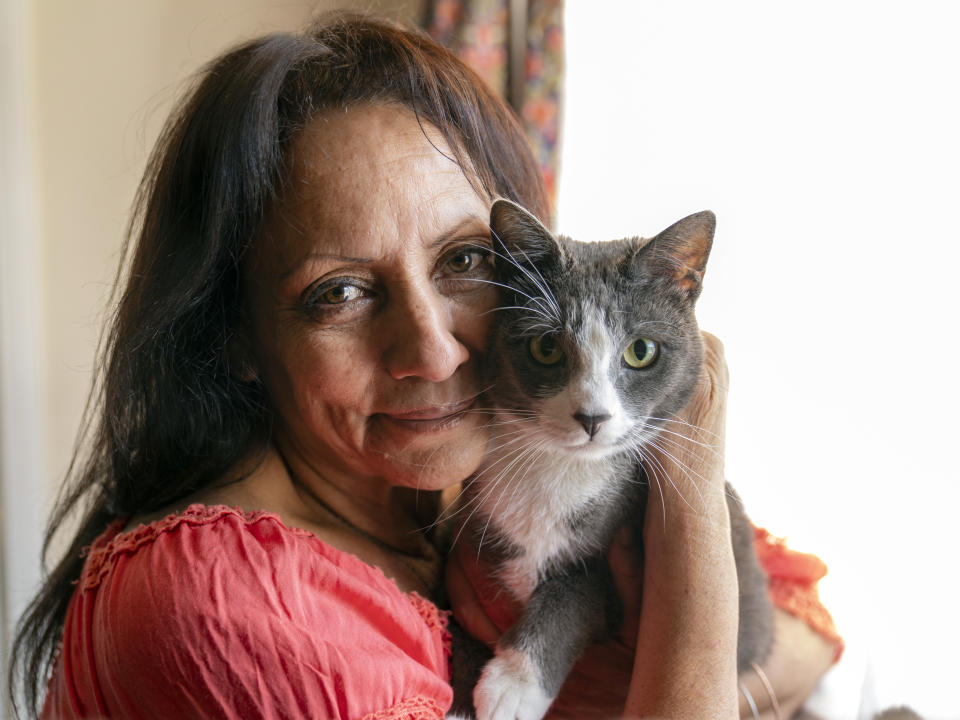 In this Wednesday, June 30, 2021, photo Veronica Perez hugs her cat, Brooklyn, at her new home at a Homekey site in Los Angeles. She took residence in one of 6,000 new units built statewide over the last year as part of Project Homekey. The California program started in June 2020 is re-purposing vacant hotels, motels and other unused properties as permanent supportive housing for the homeless. (AP Photo/Damian Dovarganes)