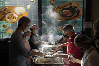 Volunteers prepare lunch boxes for low-income and street-sleepers in the area, at Dignity Kitchen in Hong Kong on Nov. 17, 2020. Located smack in the middle of Hong Kong's bustling Mong Kok neighborhood, Dignity Kitchen offers an array of mouthwatering Singaporean fare. But what sets Dignity Kitchen apart from other restaurants in the city is that it is a social enterprise, almost entirely staffed by employees with physical or mental disabilities. (AP Photo/Vincent Yu)