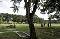 Forensic workers wait to begin an exhumation of what are believed to be the remains of Lt. Braulio Bethancourt, a victim of the 1989 U.S. invasion, at the Jardin de Paz cemetery in Panama City, Thursday, April 15, 2021. The prosecutor’s office has begun an exhumation of human remains at the Panamanian cemetery in a renewed attempt to confirm the identities of the victims of the U.S. invasion. (AP Photo/Arnulfo Franco)