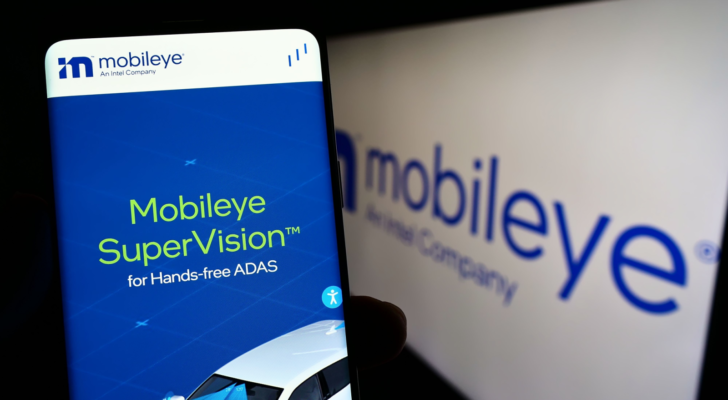 Person holding cellphone with website of Israeli autonomous driving company Mobileye (MBLY) on screen in front of logo. Focus on center of phone display. Unmodified photo.