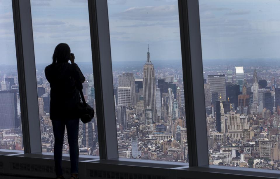 A woman photographs the Manhattan skyline from the One World Observatory observation deck on the 100th floor of the One World Trade center tower in New York