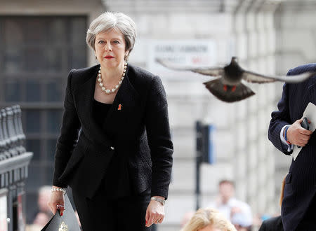 A pigeon flies ahead of Britain's Prime Minister Theresa May as she arrives at a service at St Martin-in-The Fields to mark 25 years since Stephen Lawrence was killed in a racially motivated attack, in London, Britain, April 23, 2018. REUTERS/Peter Nicholls