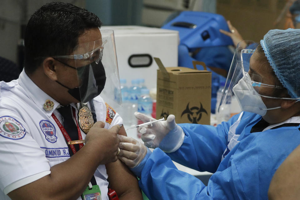 A security guard is inoculated with China's Sinovac COVID-19 vaccine at the Navotas Fish Port, Philippines on Monday, June 7, 2021. The government today bolstered its vaccination program by including frontline economic personnel both in private and government sectors. (AP Photo/Aaron Favila)